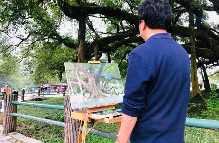 Un pittore che sta dipingendo il Grande Albero di Baniano a Yangshuo
